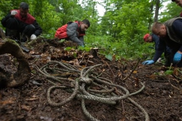 Bosnian workers, members of the Bosnian commission for missing persons inspect an area for  small body parts  near the rope used to bind victims hands during an exhumation in a small mass grave  found after testimony of an eyewitness, in remote mountain area in the village of Pelemisi, near the Bosnian town Sekovici, 50 kms northeast of Sarajevo, on Monday, May 21, 2007. The forensic team  believe that they are body parts of 6 Bosnian Muslims  held in the Susica camp in Vlasenica near Srebrenicaand killed in spring 1993 by Bosnian Serb forces.